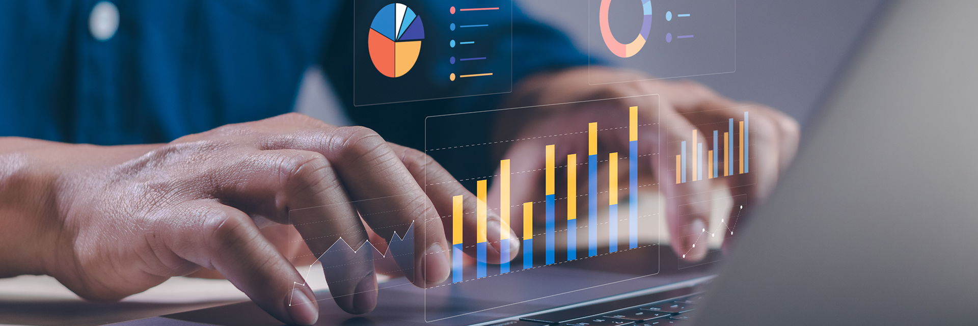 Hände tippen auf einem Laptop mit eingeblendeten digitalen Diagrammen und Analyse-Grafiken